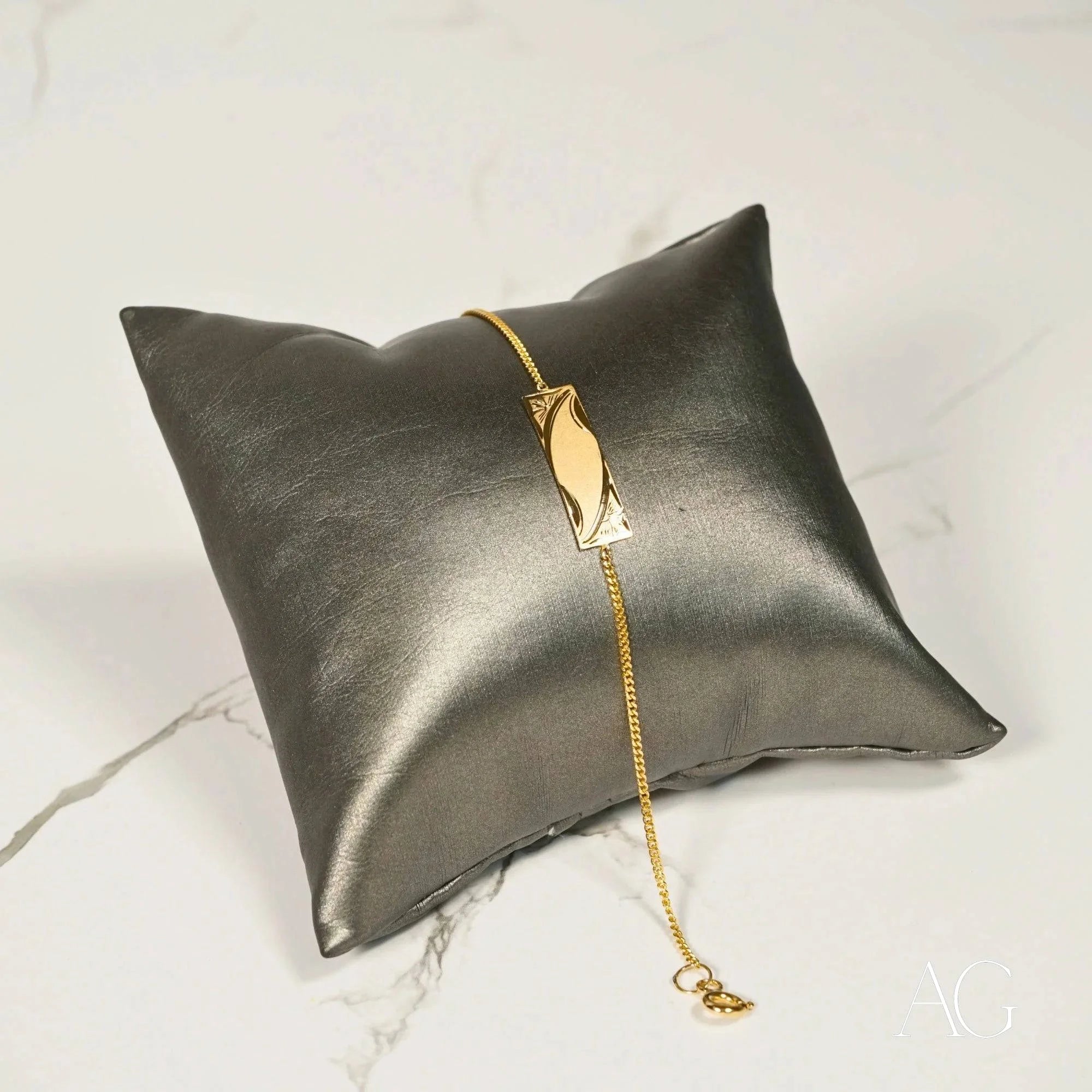 Metallic silver cushion with 18k solid gold ID bracelet for kids elegantly displayed