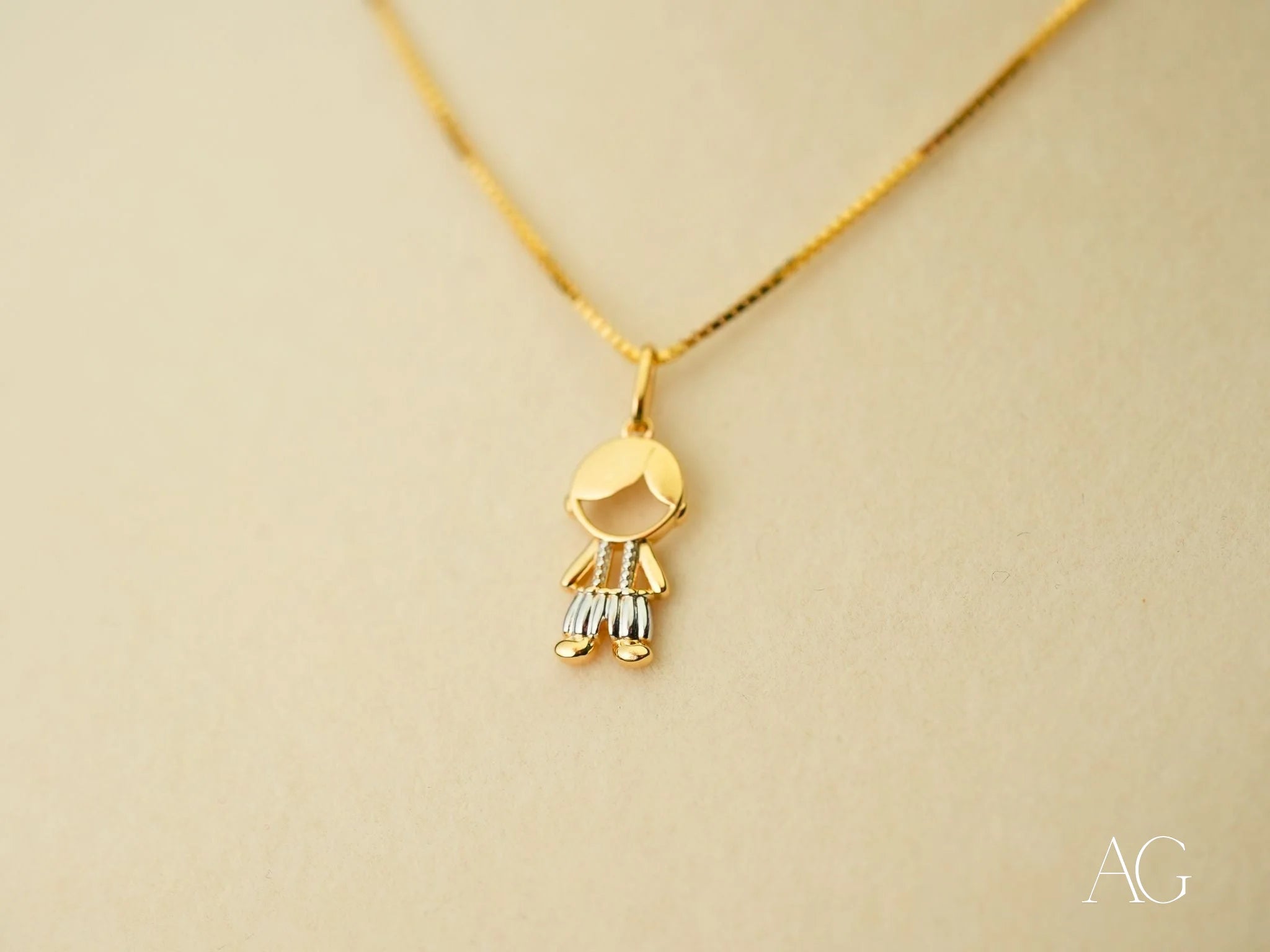 Gold pendant necklace featuring a stylized figure charm from the Timeless Charm collection