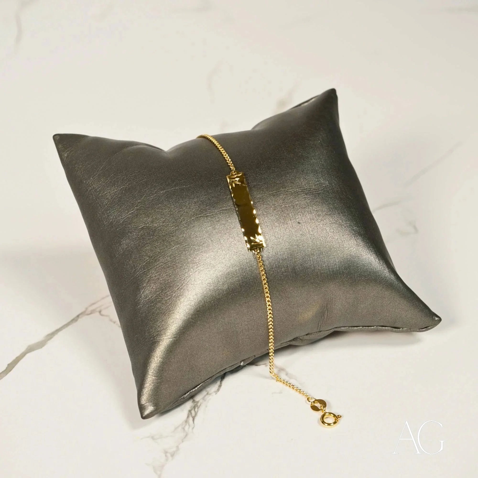 Silver satin pillow featuring a Timeless 18k solid gold ID bracelet for kids