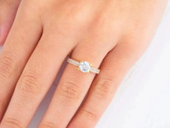 Diamond engagement ring on a finger in 18k yellow gold sparkles brightly