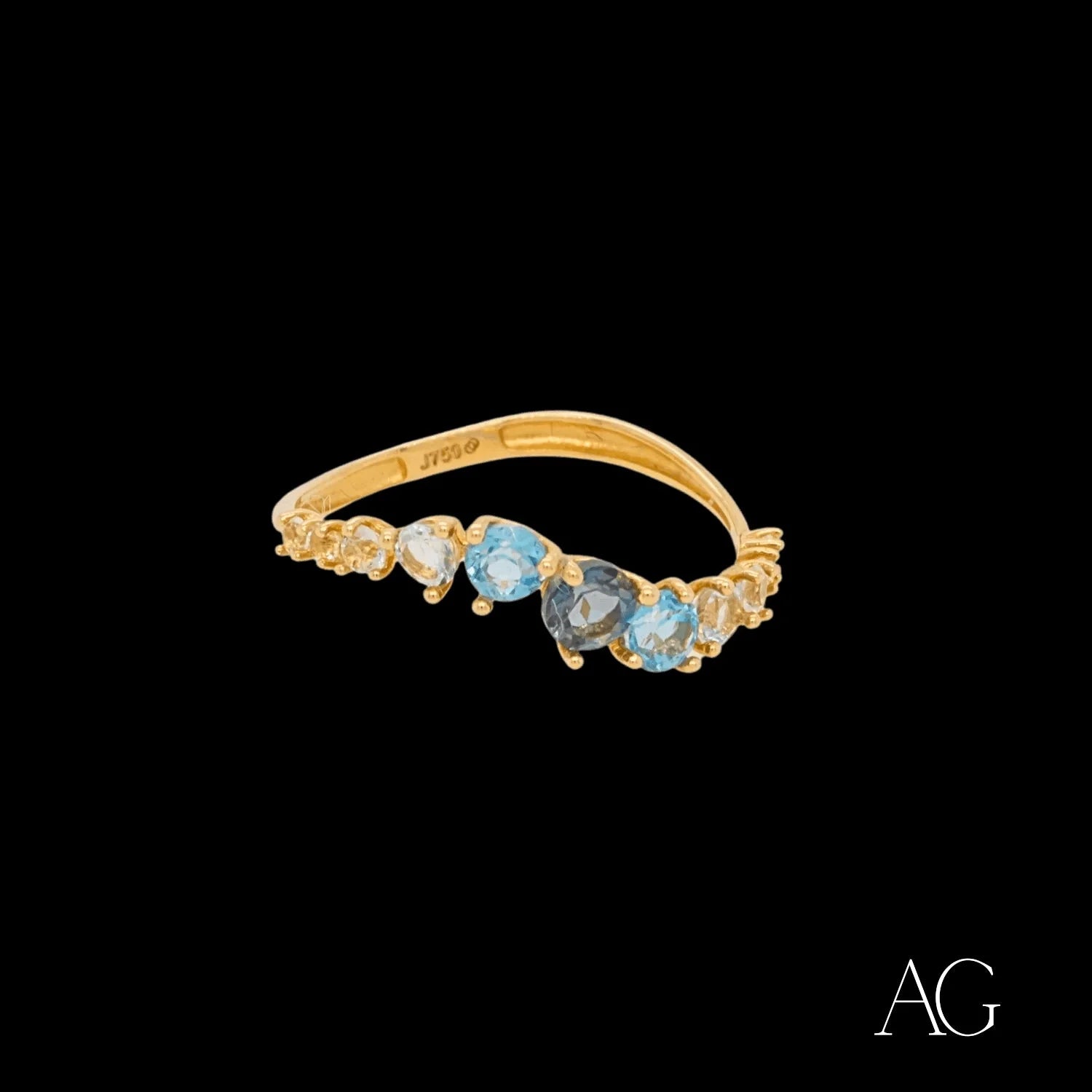 Gold ring featuring light blue gemstones in a curved design, crafted in 18k gold