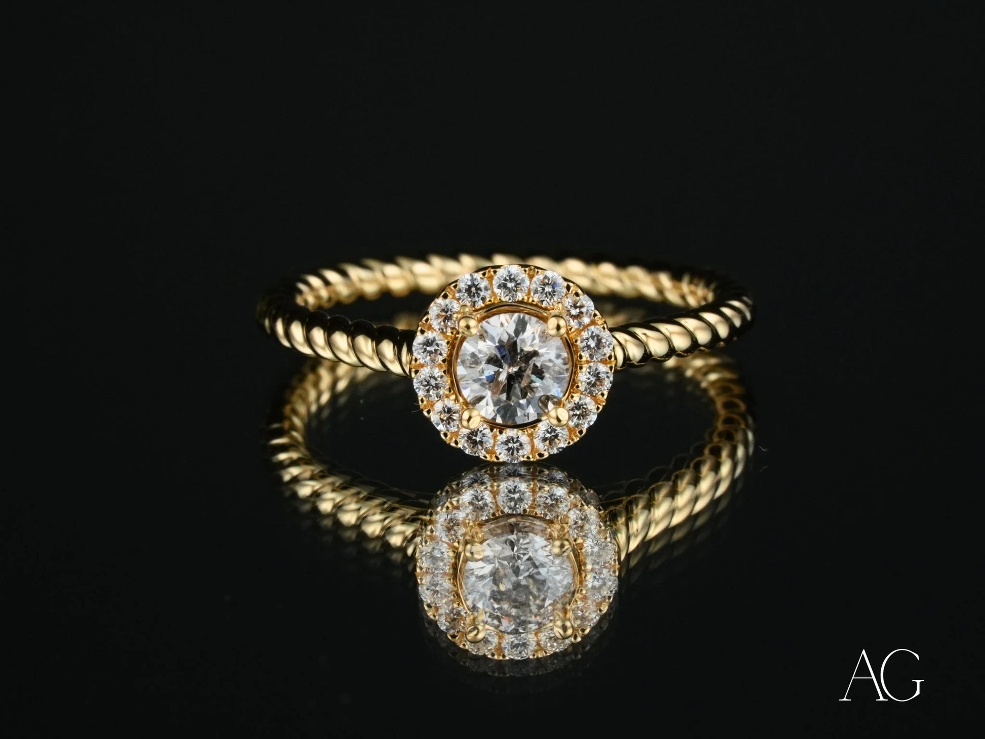 18k gold engagement ring featuring a round center diamond with a halo of smaller diamonds