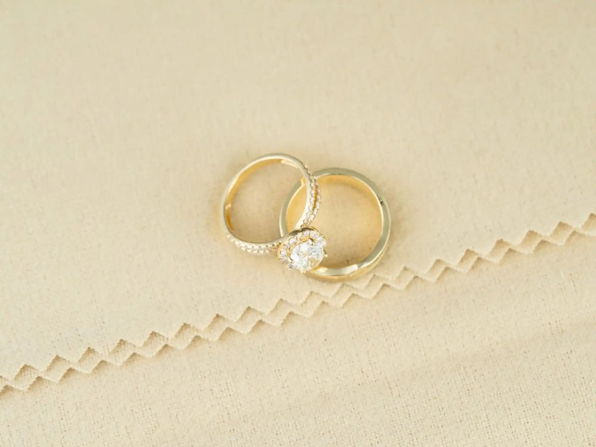 Two gold wedding rings, one with a diamond solitaire, resting together.