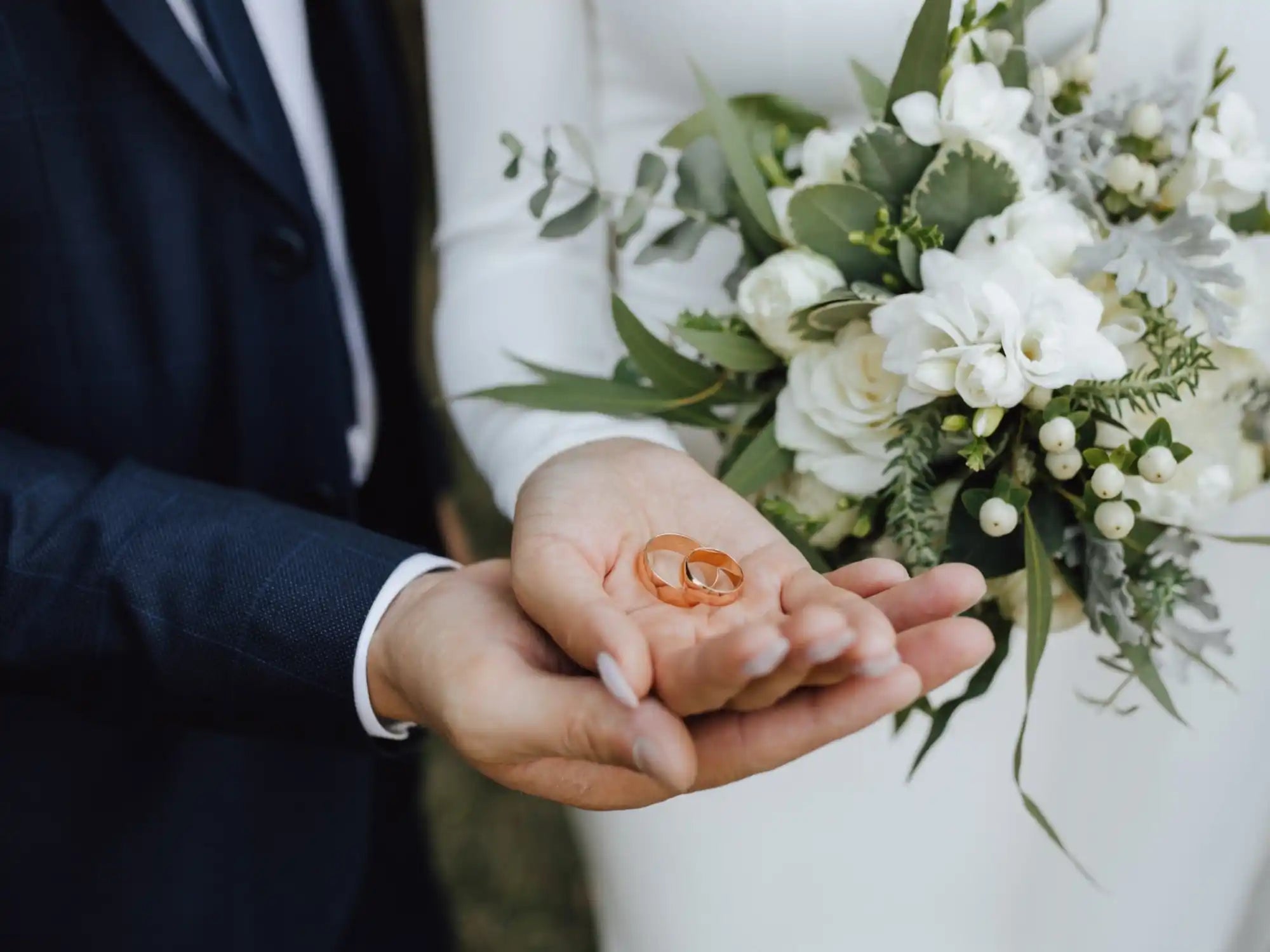 Two gold wedding rings resting in open palms.