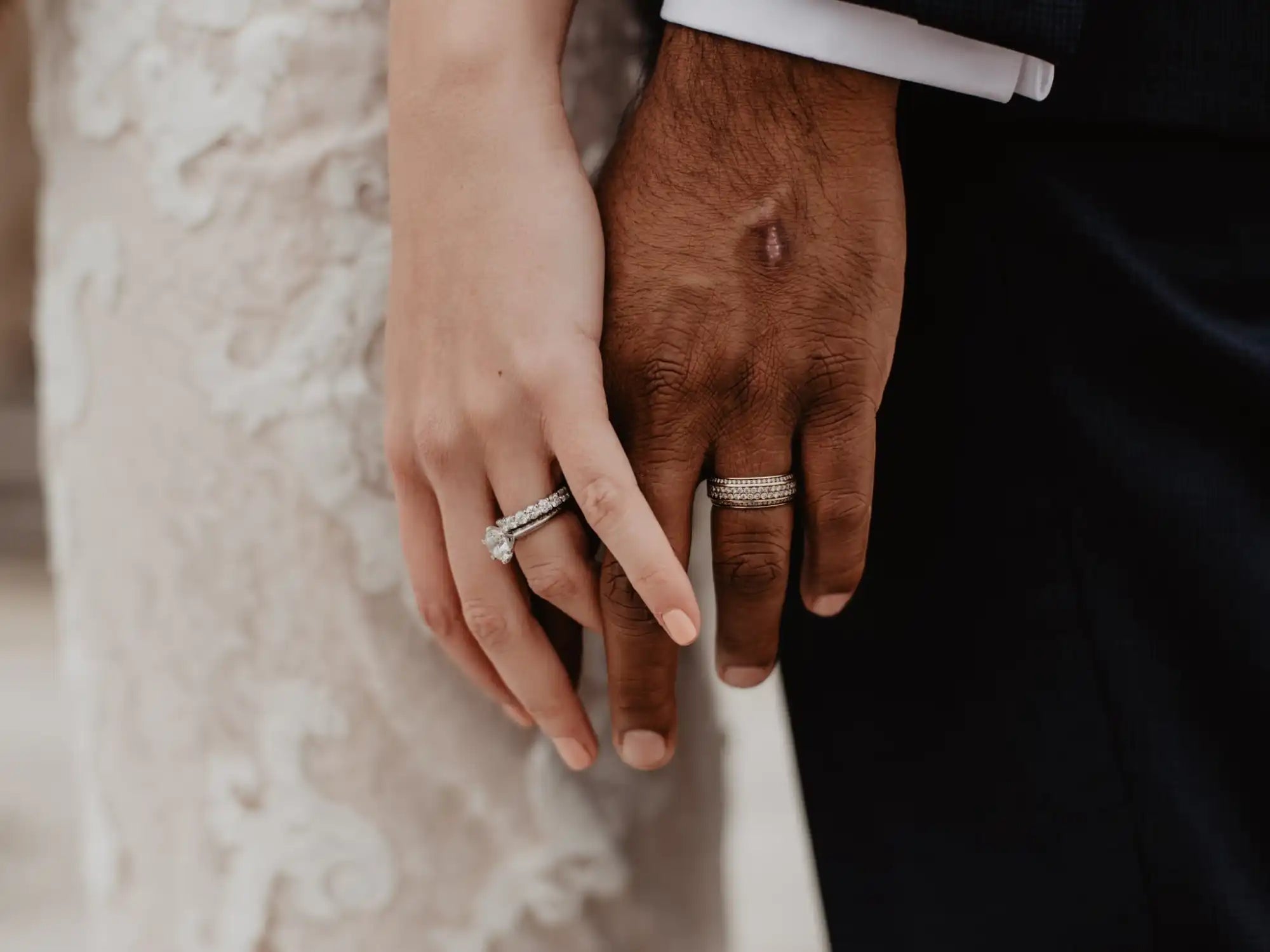 Two hands wearing wedding rings touching each other.